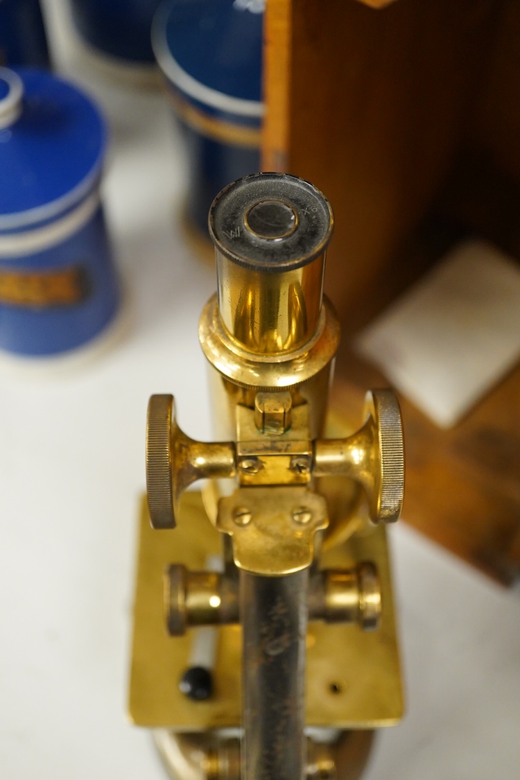 An early 20th century oak cased brass ‘Kima’ microscope by W. Watson & Sons Ltd. London, with engraved serial number under the maker’s name; 53622, with two alternative lenses in fitted compartments, microscope approxima